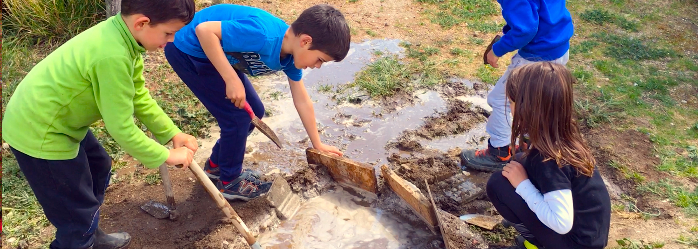 Niños cooperando para construir una presa.